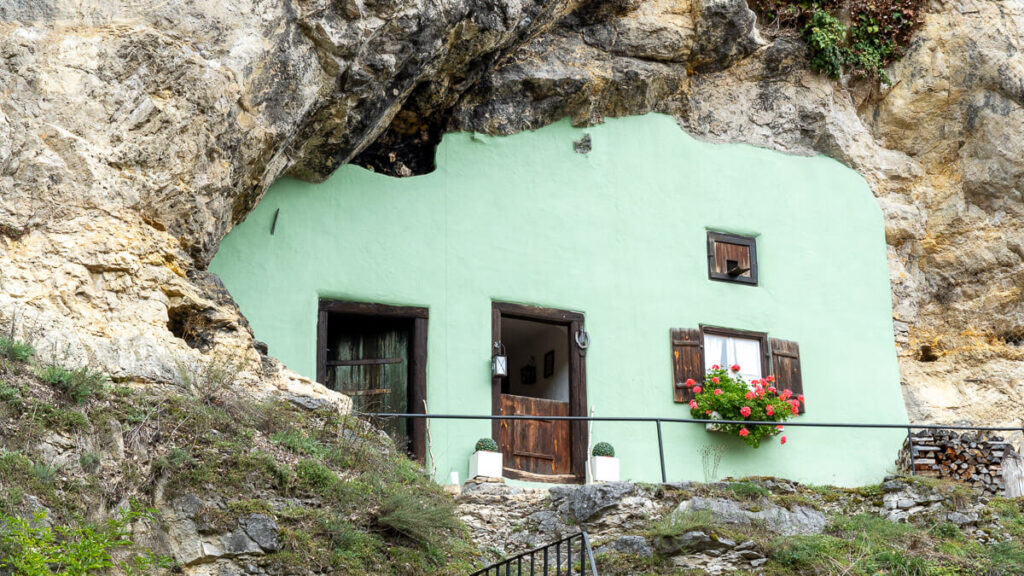 Ansicht eines Hauses, dass in die Höhle einer Felswand gebaut wurde.