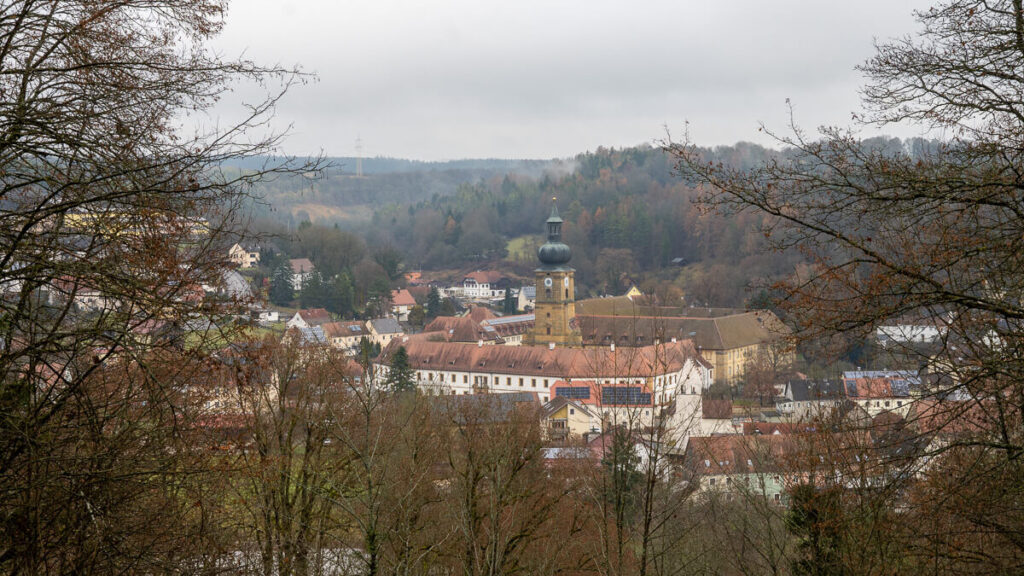 Kloster Ensdorf im Tal der Vils, durch Bäume gerahmt, auf dem Oberpfälzer Jakobsweg